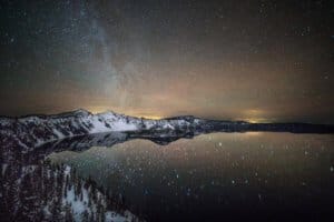Star filled astrophotography photo of Crater Lake National Park at night.