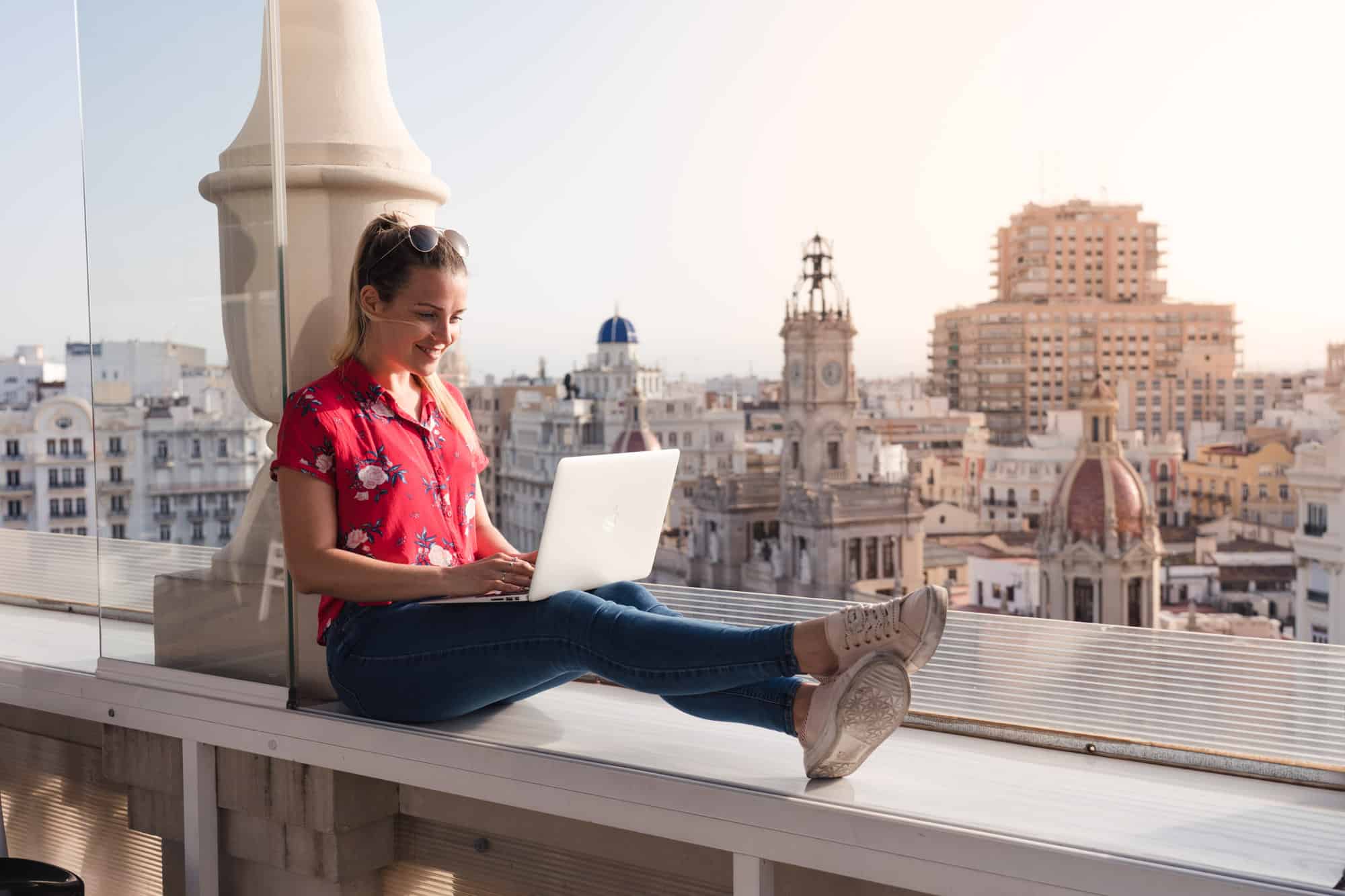 Travel photographer editing photos on Apple MacBook Pro using Adobe Photoshop Lightroom at a rooftop bar in Spair