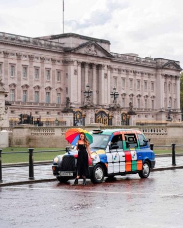 A girl and an iconic London taxi outside Buckingham Palace, one of the most instagrammable places in London