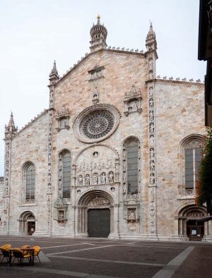The white marble facade of Duomo di Como as seen from Piaza del Duomo, Lake Como Italy. A must see on a day trip Milan to Lake Como.