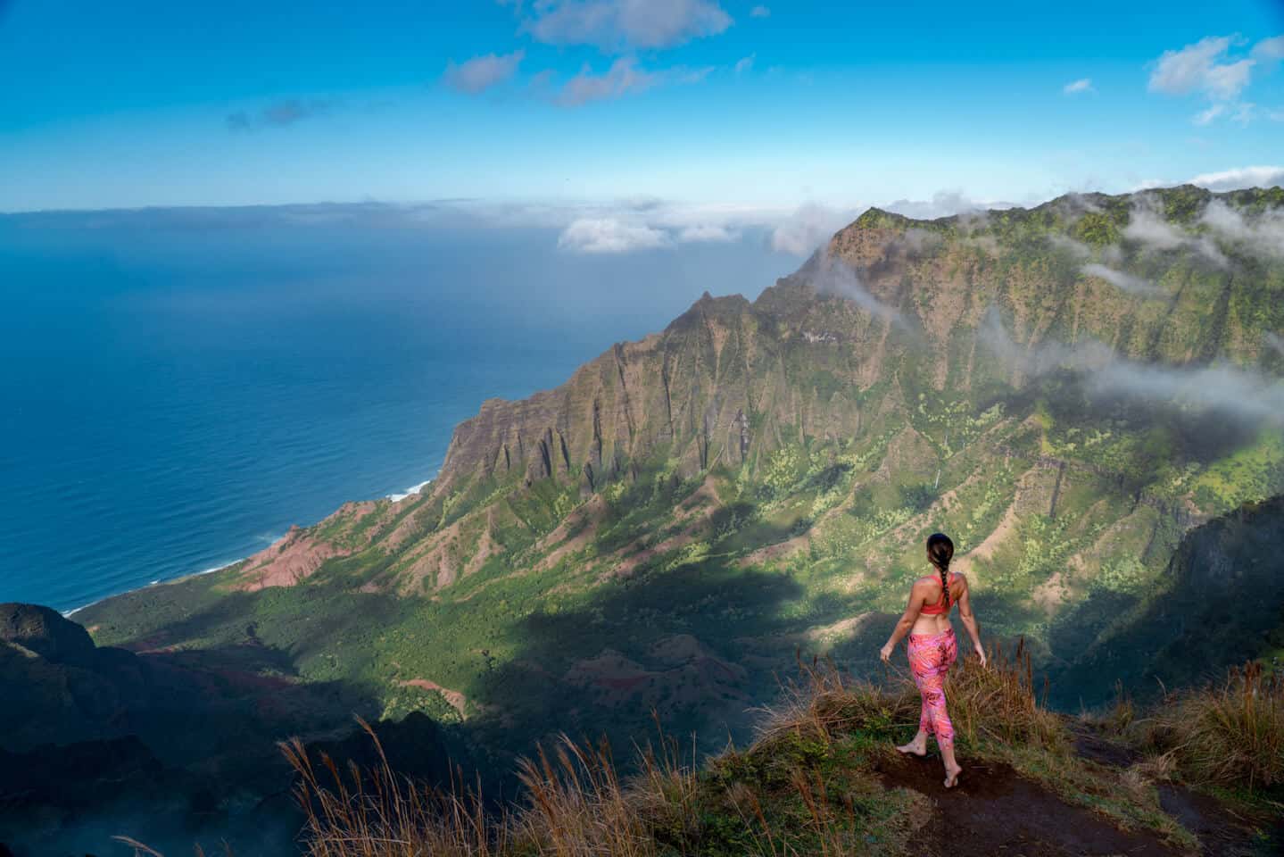 Girl standing on the edge of the Na Pali Cliffs of Kauai on the Kalepa Ridge Trail.