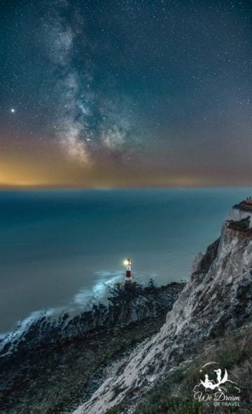 Night photography at Beachy Head Lighthouse shining against the Atlantic under a Milky Way sky.