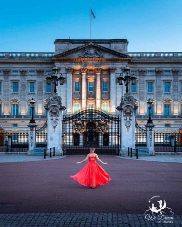 A girl in a ball gown in front of Buckingham Palace at dusk