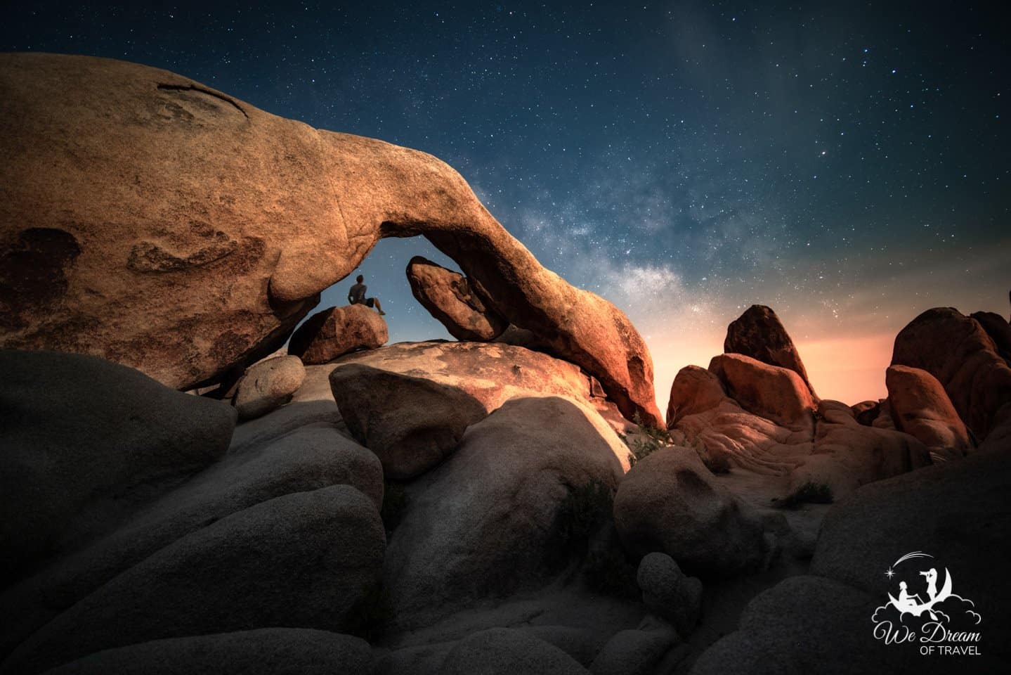 Night photography from Joshua Tree NP featuring the milky way over Arch Rock on a moonlit night.