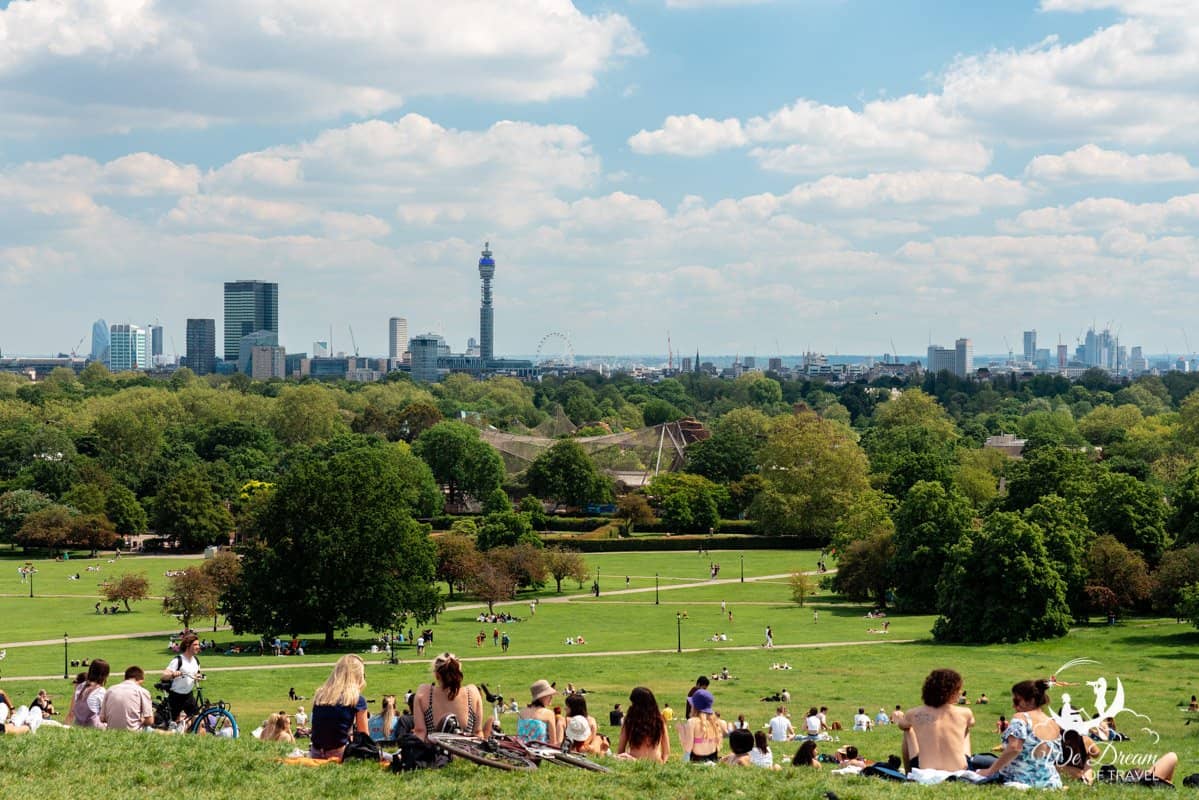 Londoners enjoying picnics in the sunshine on a summers day in Primrose Hill with spectacular views of the London skyline.