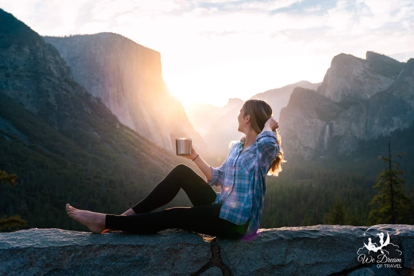 A young woman enjoys a cup of coffee during a spectacular sunrise from Tunnel View in Yosemite National Park.