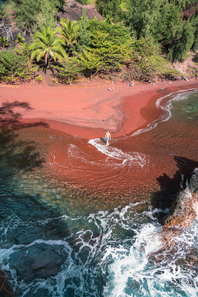 A male swimmer strolls the shore of Kaihalulu Red Sand Beach on the Hana Hwy in Maui.