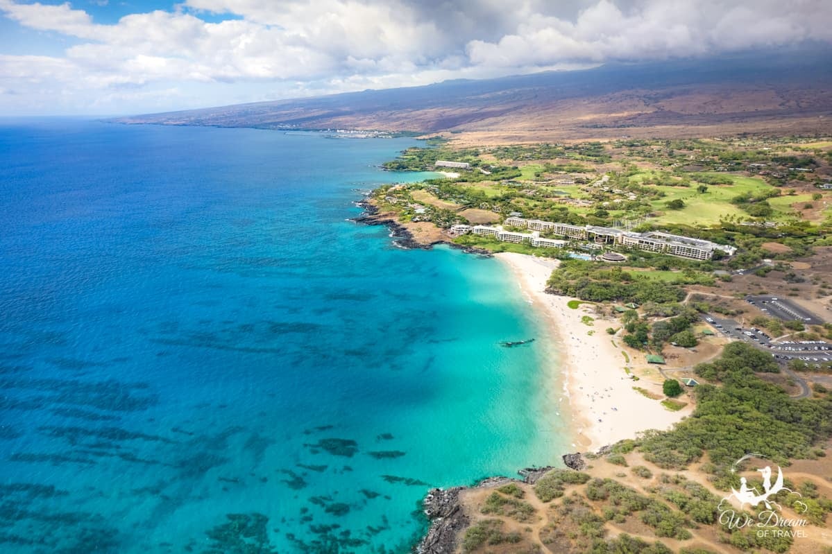 Hapuna Beach in North Kona is captured from a drone revealing the crystal clear blue water and white sand beach of the Kohala Coast.
