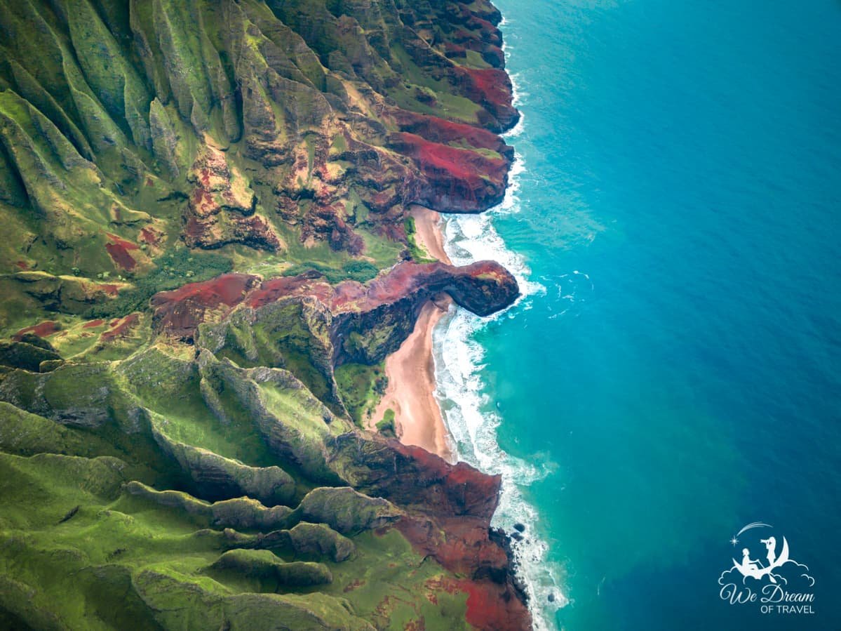 Aerial view from the sky looking down onto a beach and the Napali Cliffs on a Napali Coast tour in Kauai.