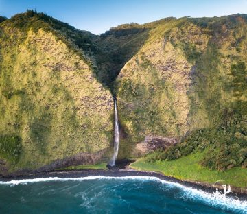 Drone photo of a waterfall spilling into the Pacific Ocean in the Waipio Valley