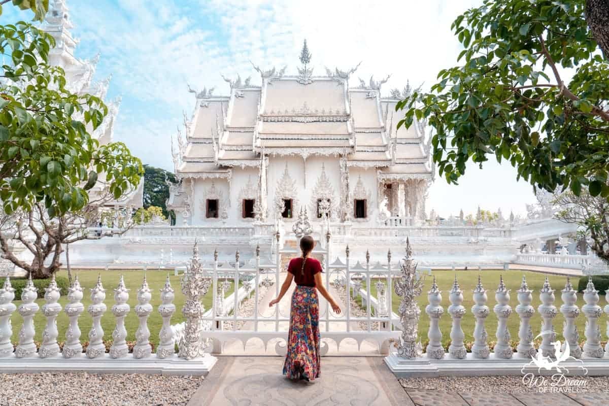 A photo showing the White Temple in Chiang Rai from the side of the building standing at the gate.