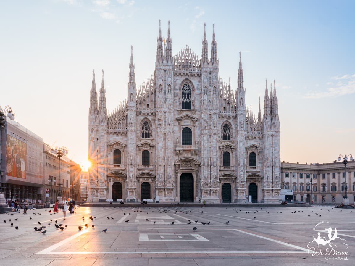 Piazza di Duomo at sunrise showing a sunstar appearing behind Milan Cathedral