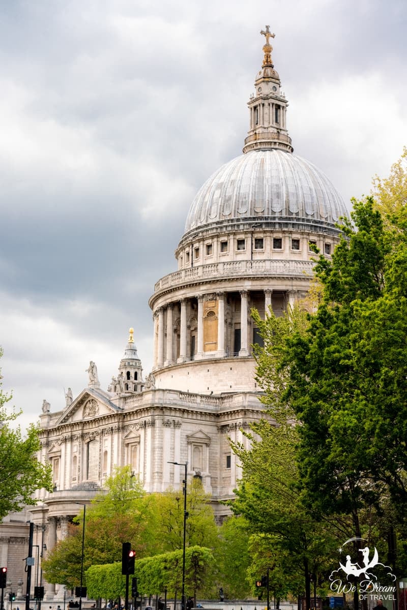 Exterior of St Paul's Cathedral framed by green foliage.