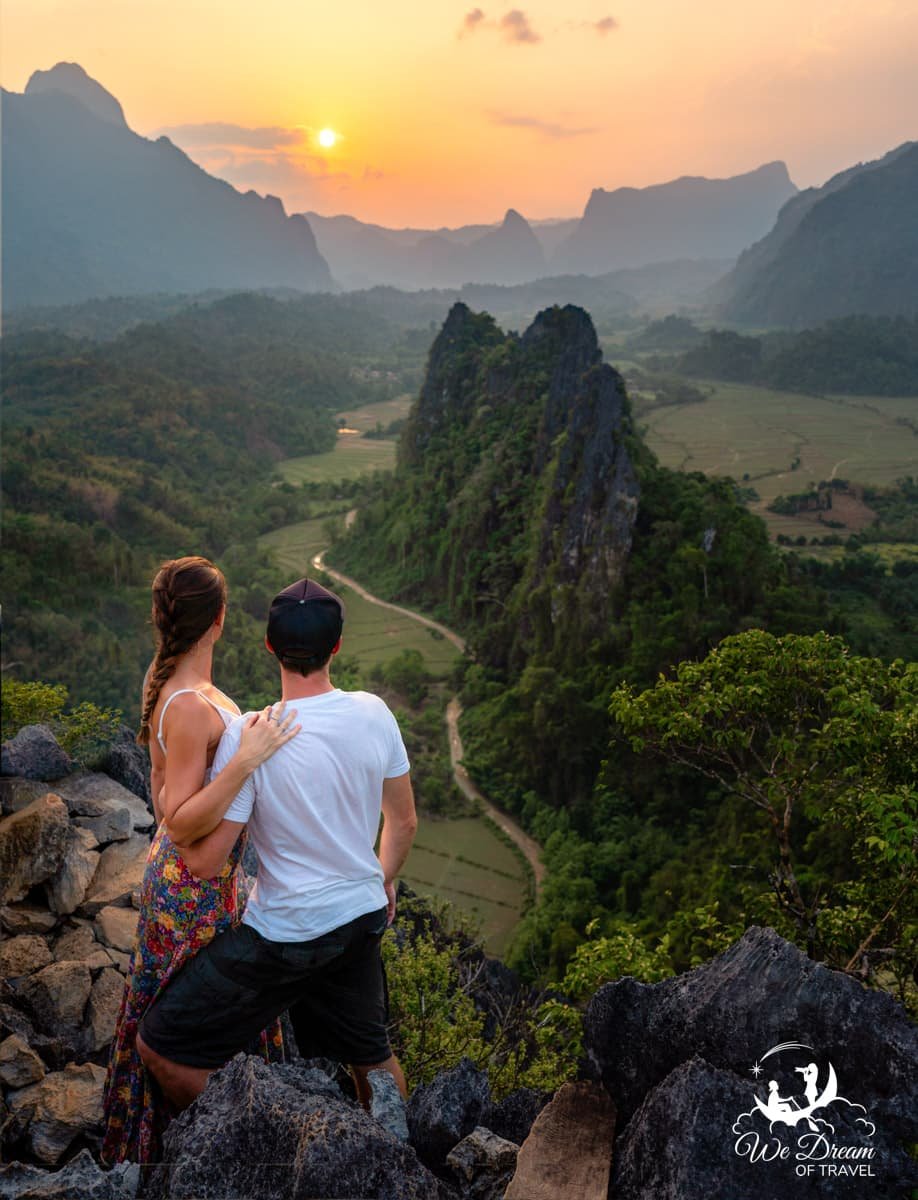 A young couple looking out over a rugged, lush landscape from Nam Xay viewpoint in Laos.