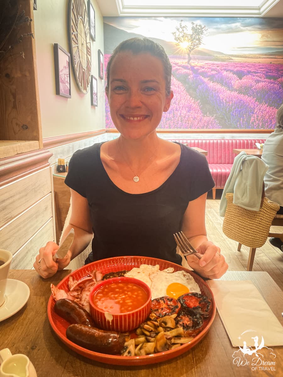 Sophie Marland with a big smile on her face, sat in a cafe with a full English breakfast in front of her.